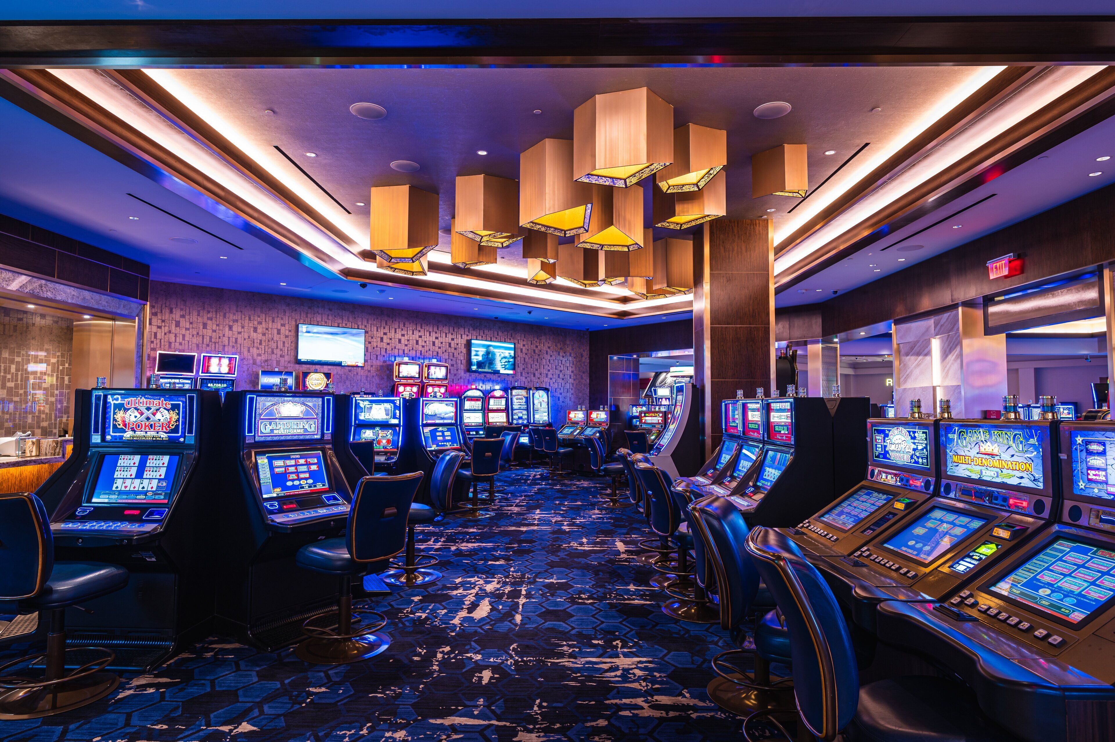 A casino with multiple slot machines and a carpeted floor.