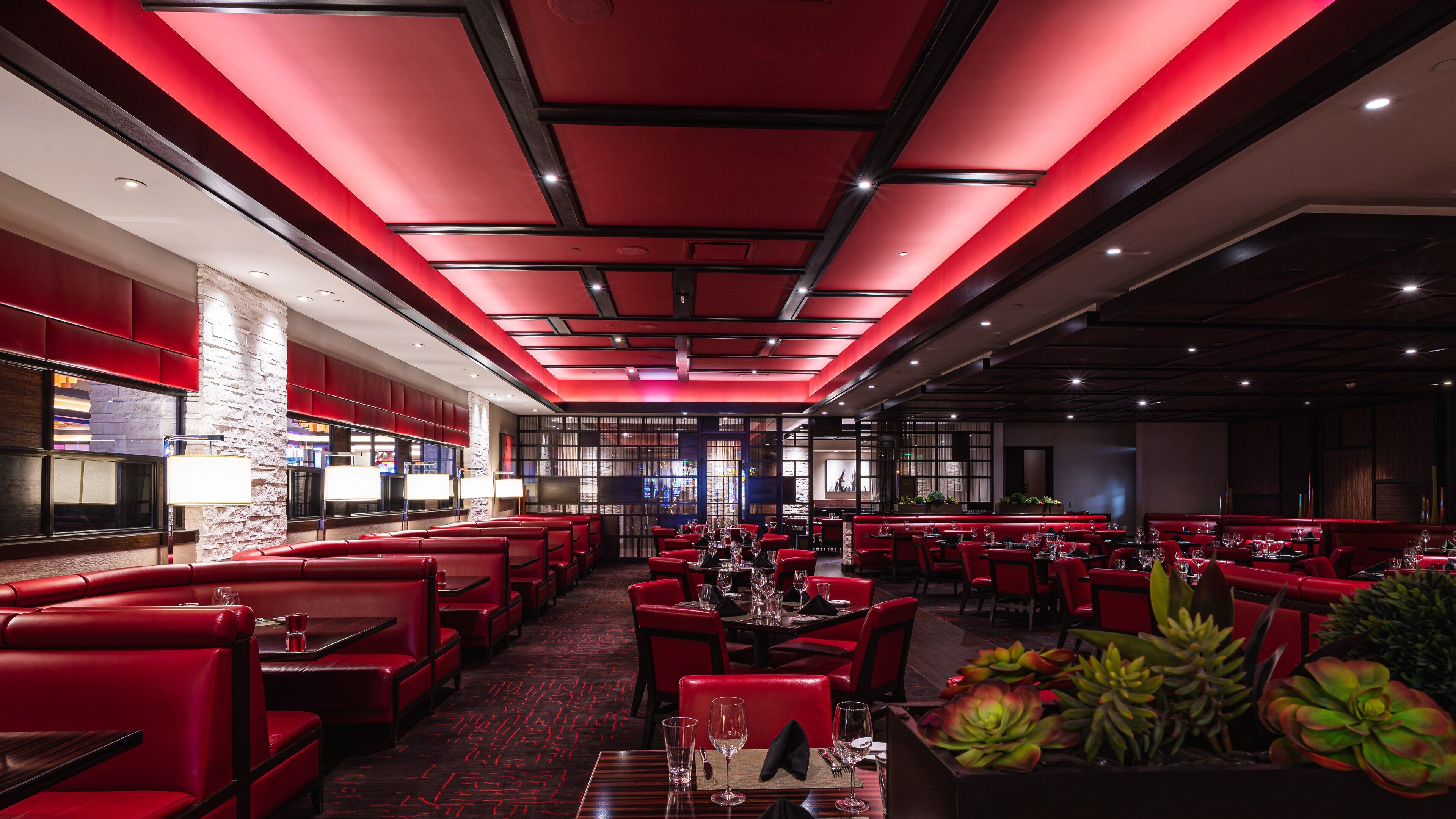 A modern restaurant with red seating, a stone accent wall, and a red ceiling.