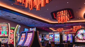 A casino interior with slot machines, a geometric patterned floor, and modern lighting fixtures.
