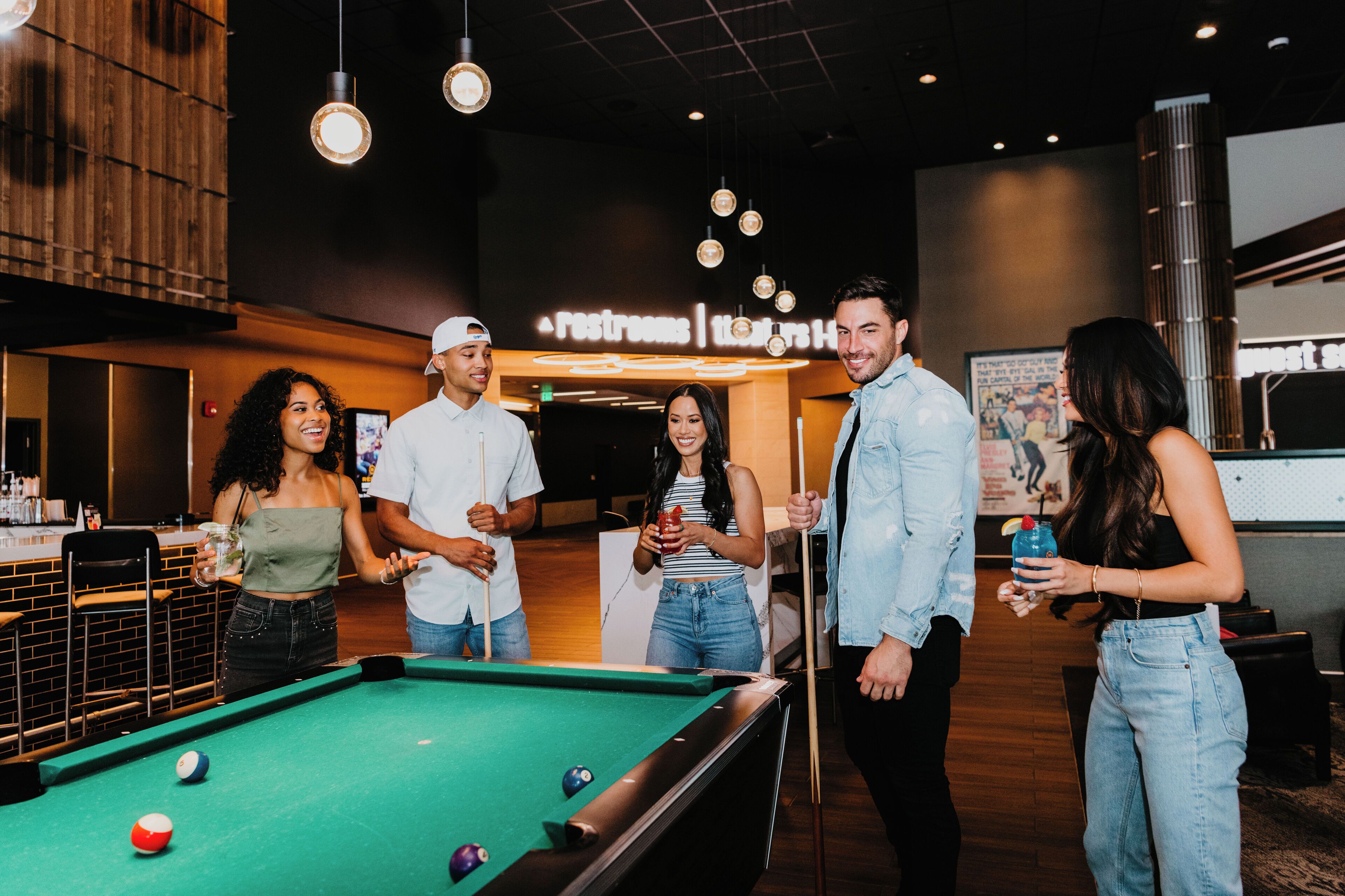 A pool table in a modern indoor setting with a sign indicating a restroom and a health bar.