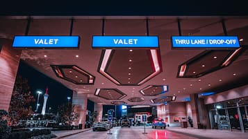 A hotel entrance with 'VALET' signs and a 'THRU LANE / DROP-OFF' sign.