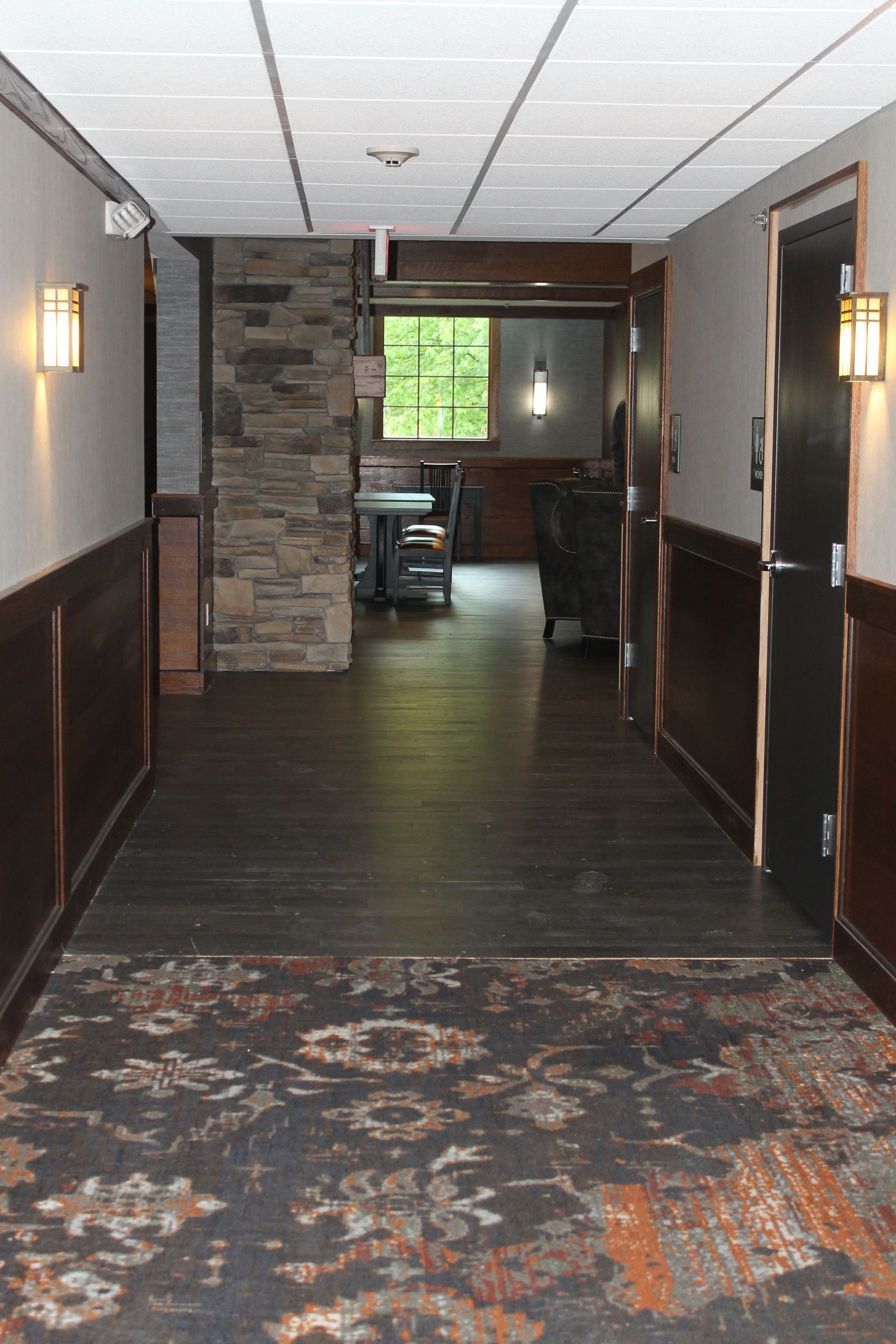 A hallway with a stone wall, a window, and a seating area with chairs and a table.