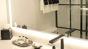 Un baño moderno con un espejo grande, un lavabo blanco y una ducha con cerramiento de vidrio.