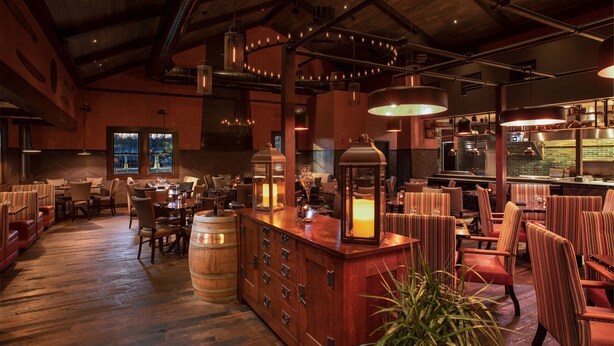 A spacious restaurant with wooden floors, a central bar area, and multiple seating options.