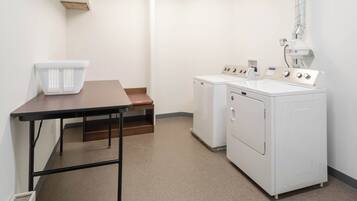 A laundry room with a table, a bench, and two washing machines.