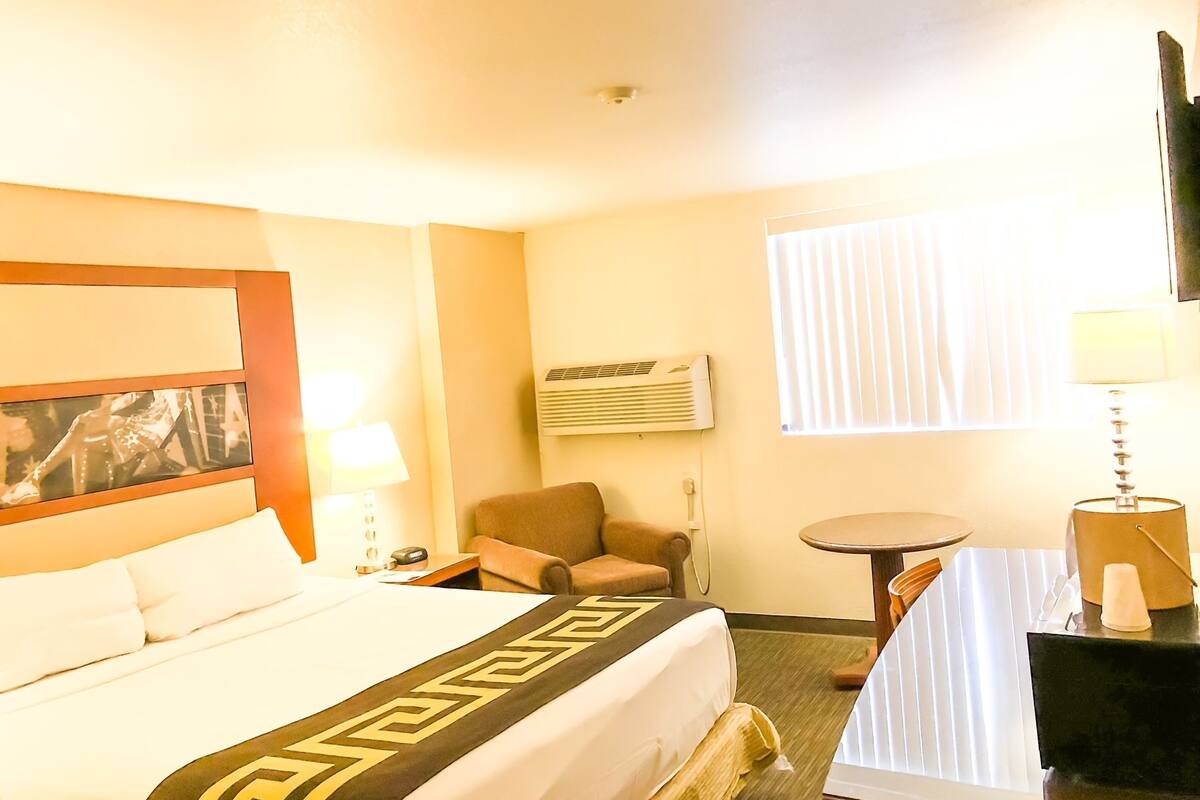 A hotel room with a bed, a chair, a small table, and a TV.