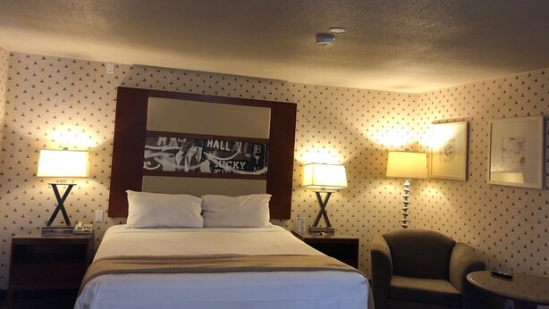 Une chambre d’hôtel avec un grand lit, deux lampes de chevet, une chaise et une petite table.
