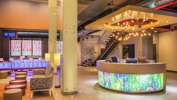 Un vestíbulo moderno de hotel con recepción, área de descanso y una escalera.