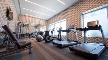 Un gimnasio con cintas de correr, elípticas y equipo de levantamiento de pesas.