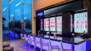 A bar area with a neon sign, bar stools, and a well-lit interior. - Aloft by Marriott New York LaGuardia Airport (East Elmhurst)