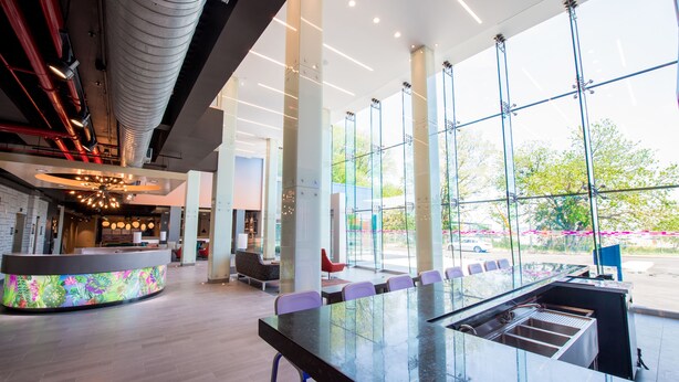 A modern lobby with a reception desk, seating area, and large windows offering views of the outdoors. - Aloft by Marriott New York LaGuardia Airport (East Elmhurst)