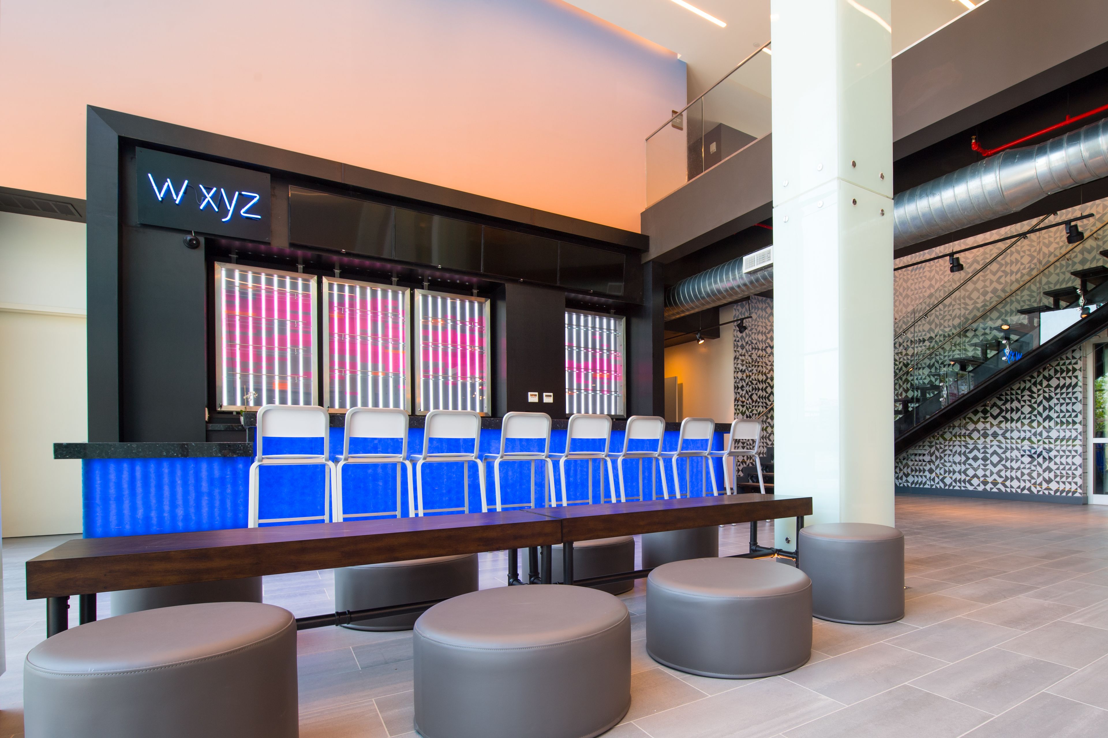 A reception area with a long counter, blue chairs, and grey ottomans.