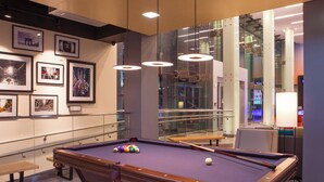 A pool table with balls, a bench, and framed pictures on the wall. - Aloft by Marriott New York LaGuardia Airport (East Elmhurst)