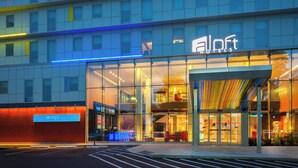 A hotel with a modern glass facade, a prominent 'aloft hotels' sign, and a 'WXYZ' sign on the left. - Aloft by Marriott New York LaGuardia Airport (East Elmhurst)