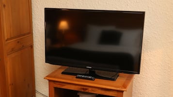 A flat-screen TV on a wooden stand with a remote control.