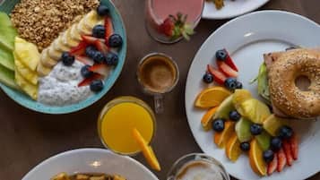 A breakfast spread with toast, eggs, fruit, granola, and beverages.