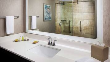 Un baño moderno con un espejo grande, un lavabo con tocador y una zona de ducha.