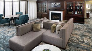 A modern living room with a sectional sofa, a round coffee table, and a fireplace. - DoubleTree by Hilton Nashua (Nashua)
