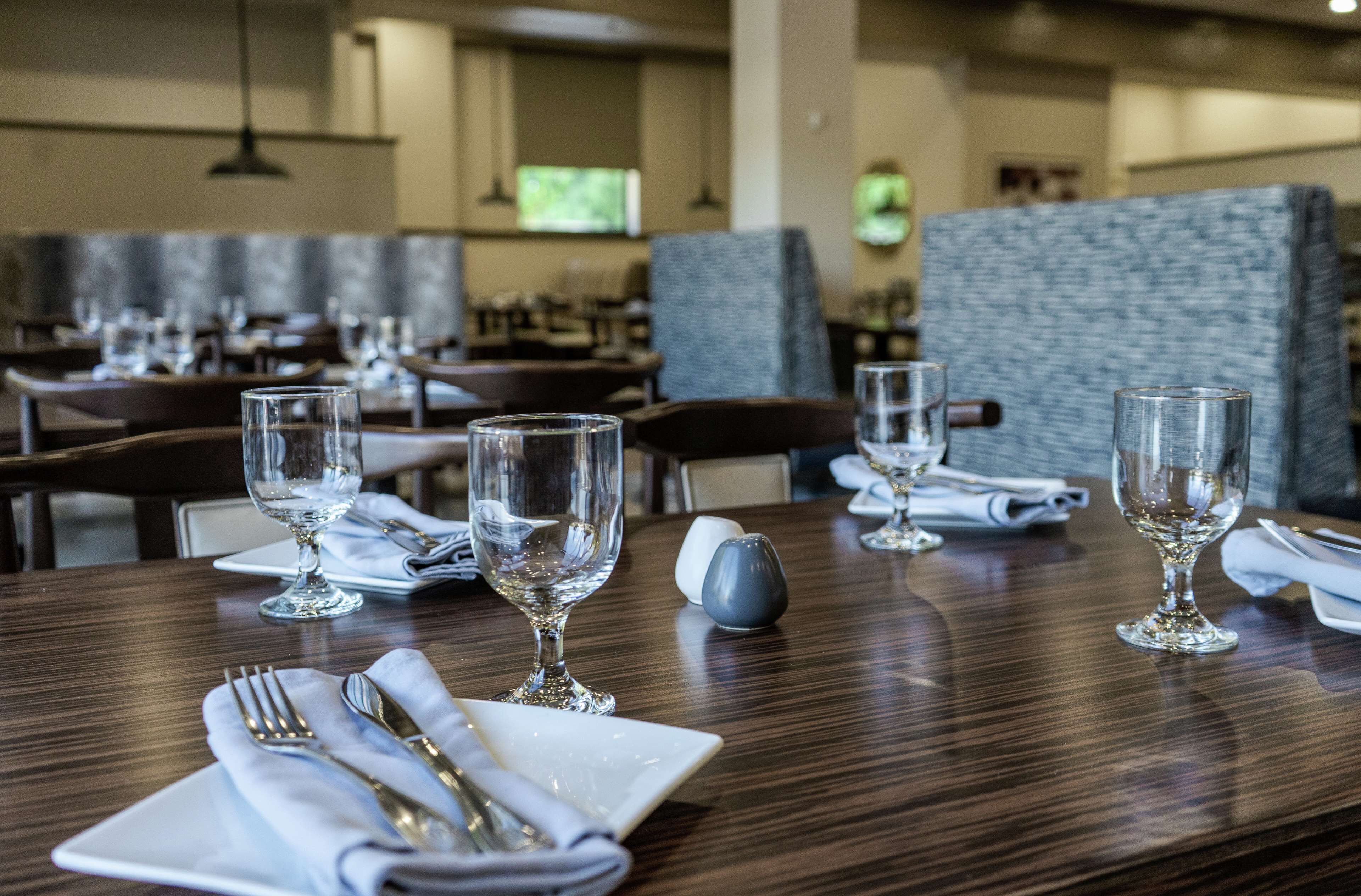 A restaurant with wooden tables, clear glassware, and neatly folded napkins.