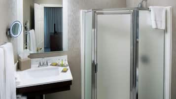 A bathroom with a glass shower enclosure, a sink with a mirror, and a towel rack.