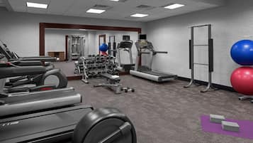Ein Fitnessraum mit Laufbändern, Crosstrainern, Hantelbänken und Trainingsbällen.