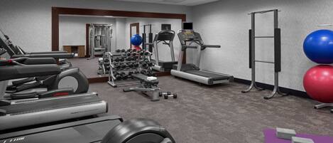 A gym with treadmills, elliptical machines, weight benches, and exercise balls.