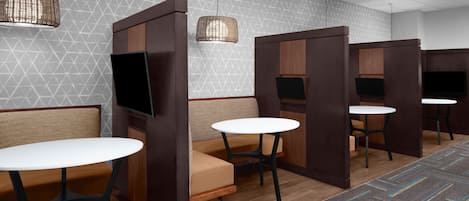 A modern room with partitioned seating areas, each with a table and a television.