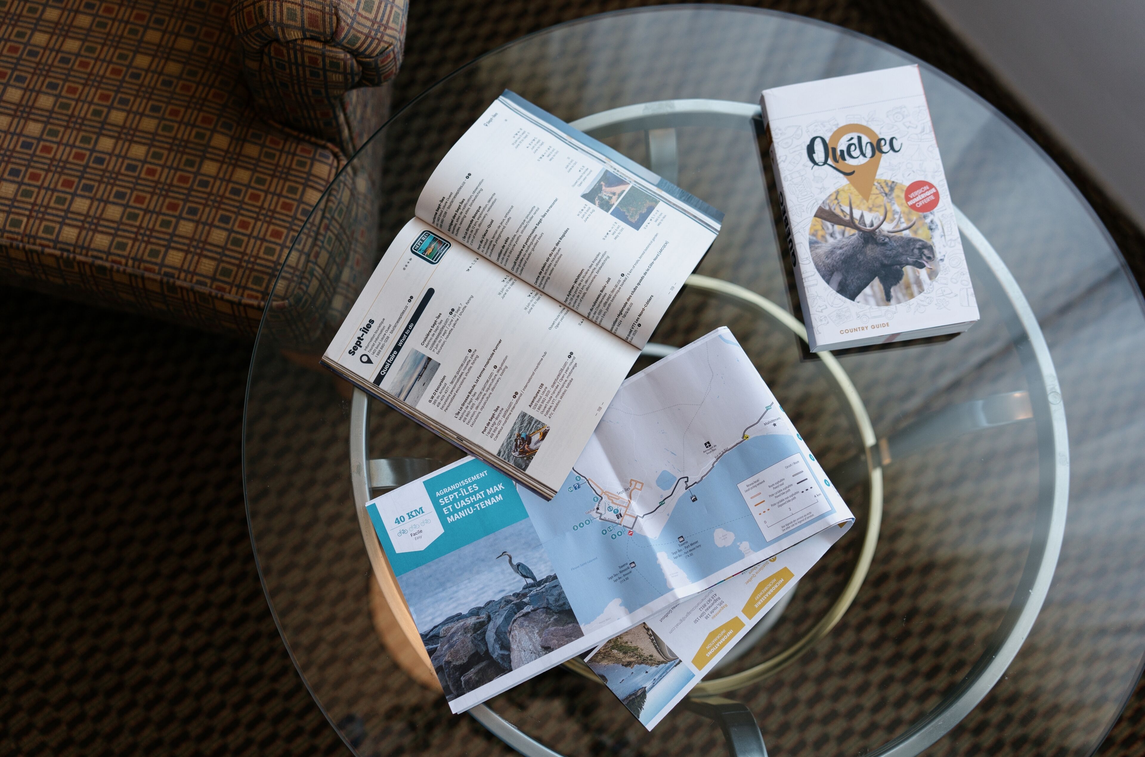 A glass table with brochures and a book titled "Quebec" on it.
