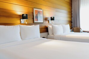 A hotel room with two beds, wooden panel walls, and wall-mounted lamps. - Hôtels Gouverneur Sept-Îles (Sept-Iles)