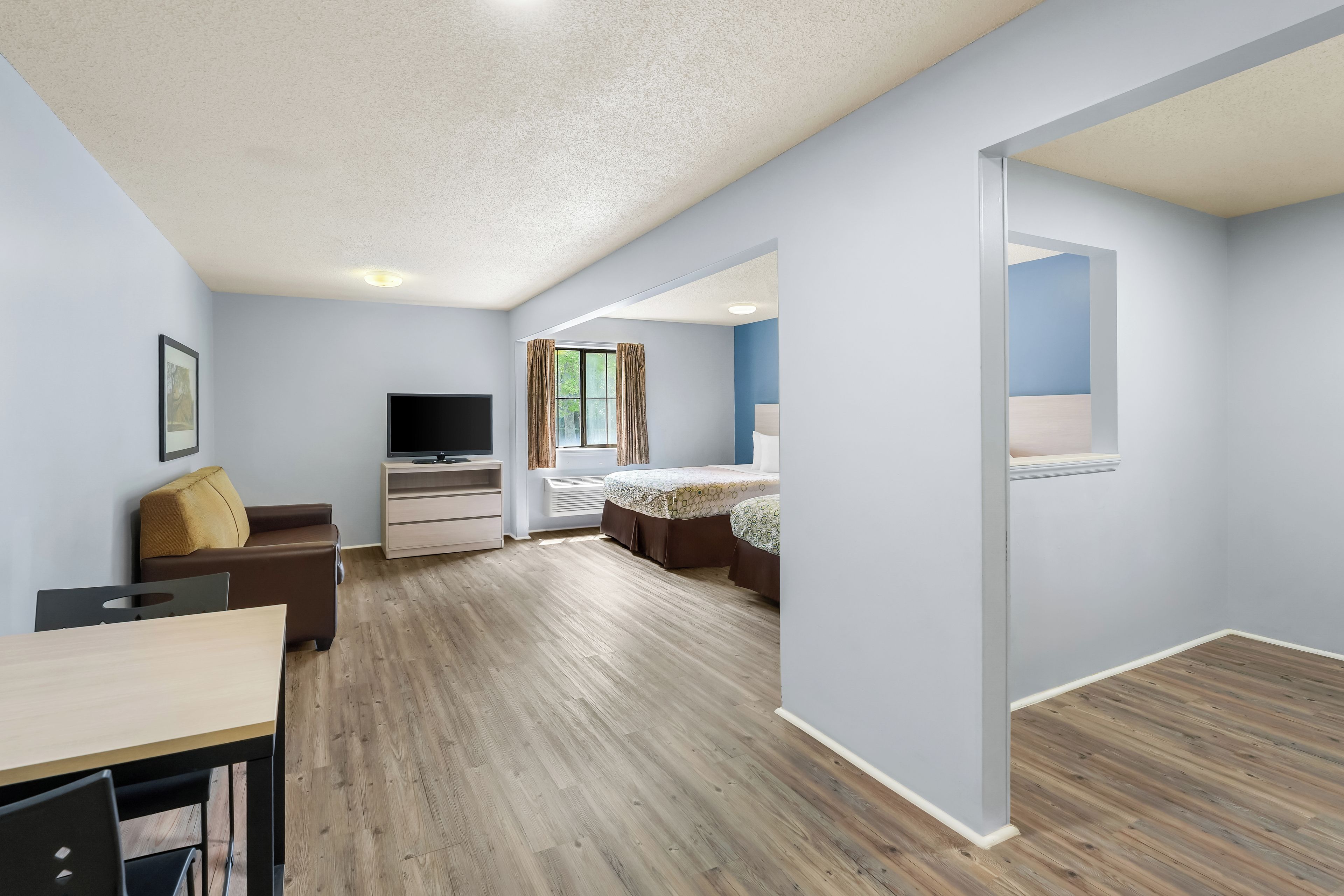 A modern hotel room with a flat-screen TV, a sofa, a desk, and a bed.