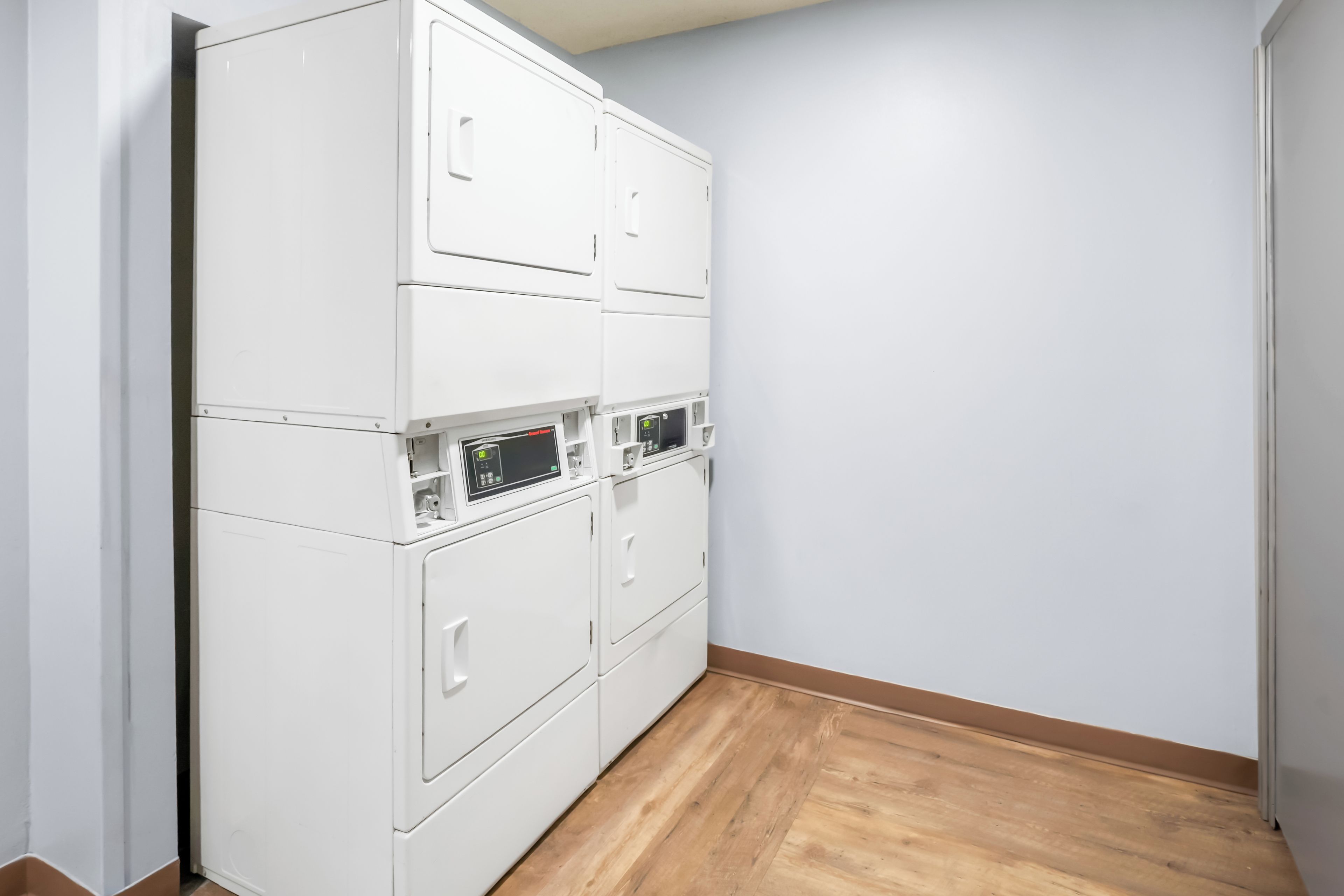 Un lavadero con armarios blancos apilados y piso de madera.