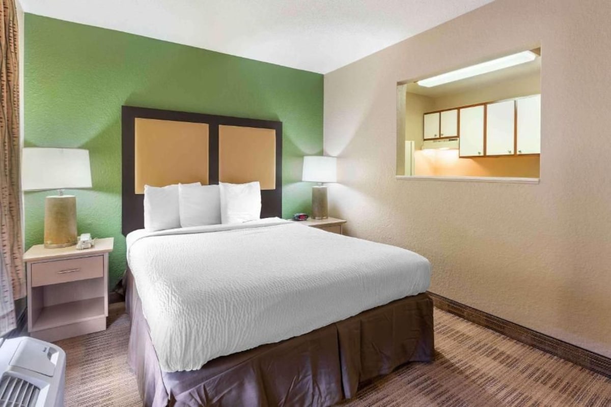A hotel room with a bed, bedside tables, lamps, and a window.