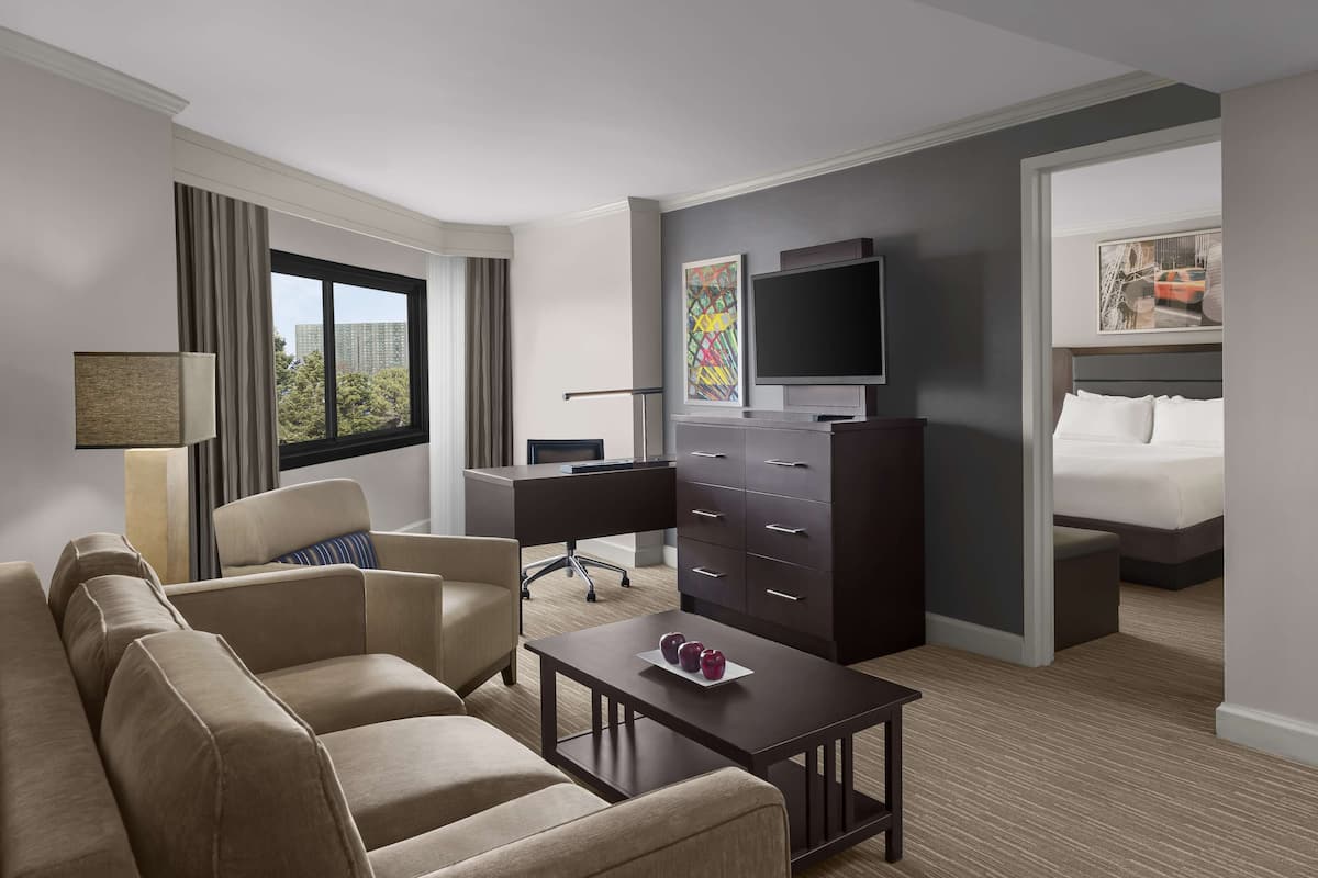 A hotel room with a sofa, a desk, a dresser, a TV, and a bed.