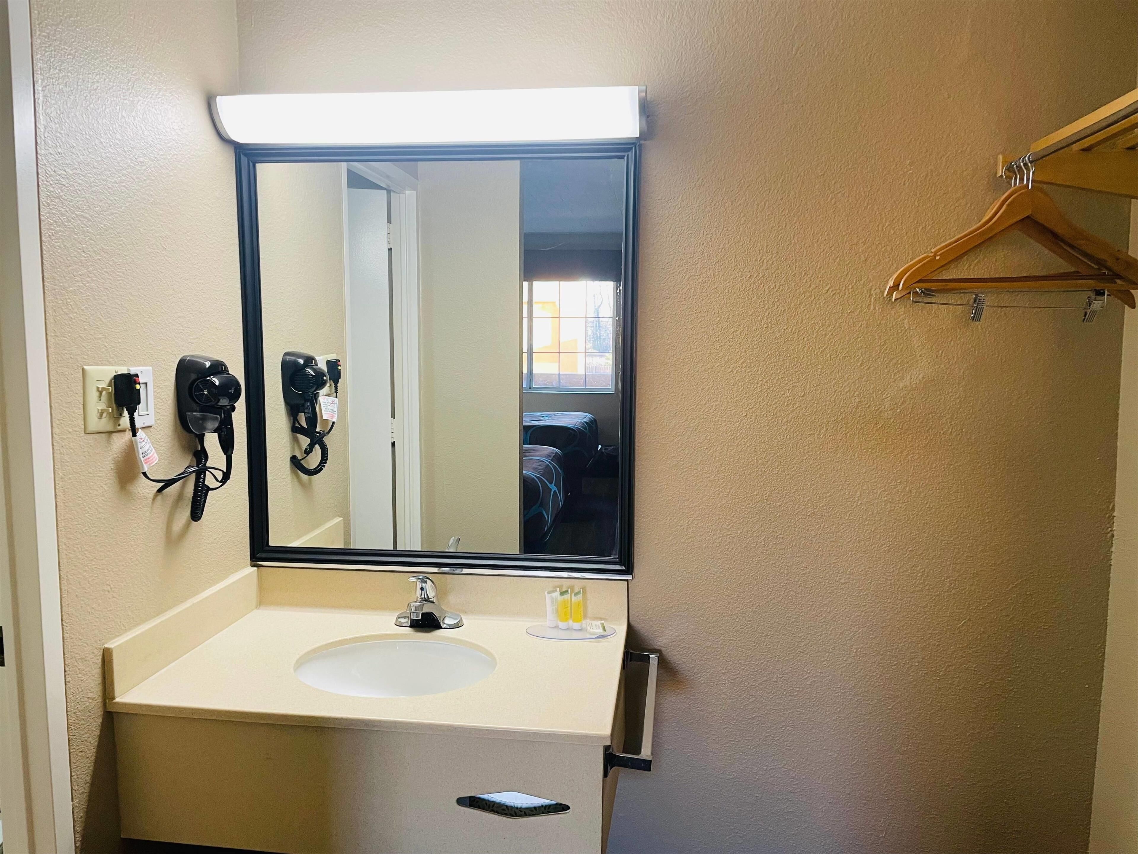 A bathroom with a sink, mirror, and hairdryer.