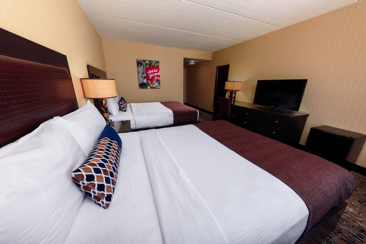 Une chambre d’hôtel avec deux lits, une télévision et un bureau avec une lampe.