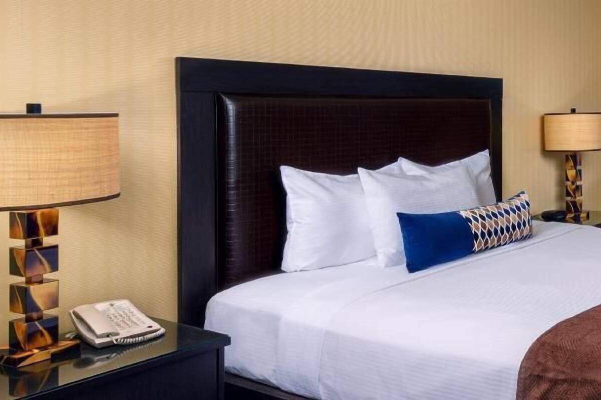 Une chambre d’hôtel avec un lit, une table de chevet avec une lampe et un téléphone.