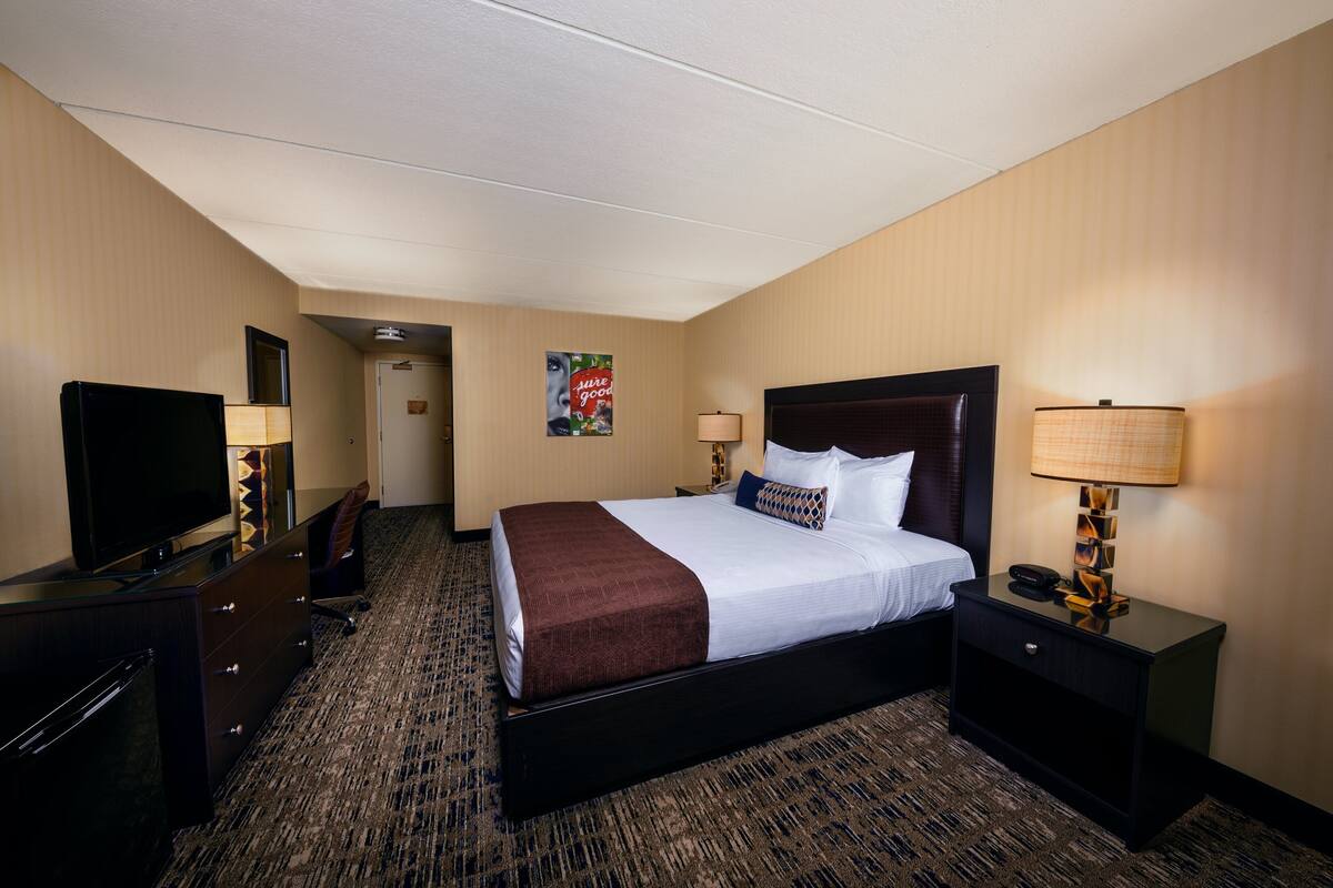 Une chambre d’hôtel avec un lit, une télévision, un bureau et une lampe.
