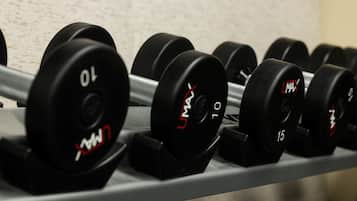 A row of black dumbbells with weight markings on a rack.
