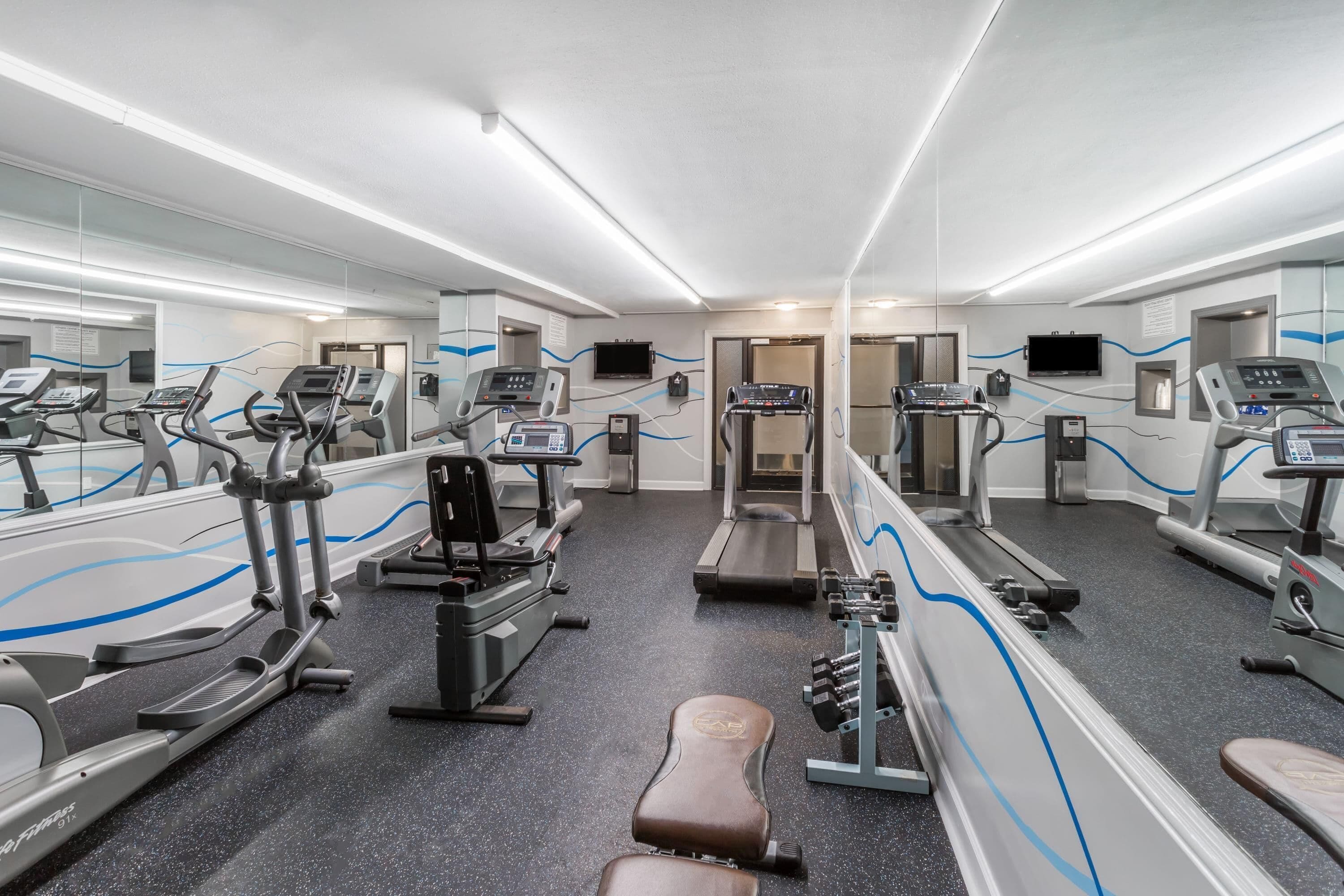 A gym with treadmills, elliptical machines, and weight benches.