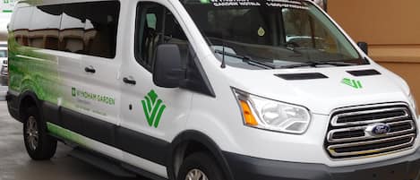 Una camioneta blanca con la marca WYNDHAM GARDEN HOTELS en verde y negro, estacionada en un estacionamiento.