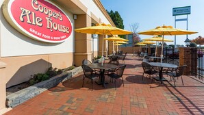Un área de patio al aire libre con mesas y sillas, un letrero de Cooper's Ale House y un letrero del Hotel Wyndham Garden.