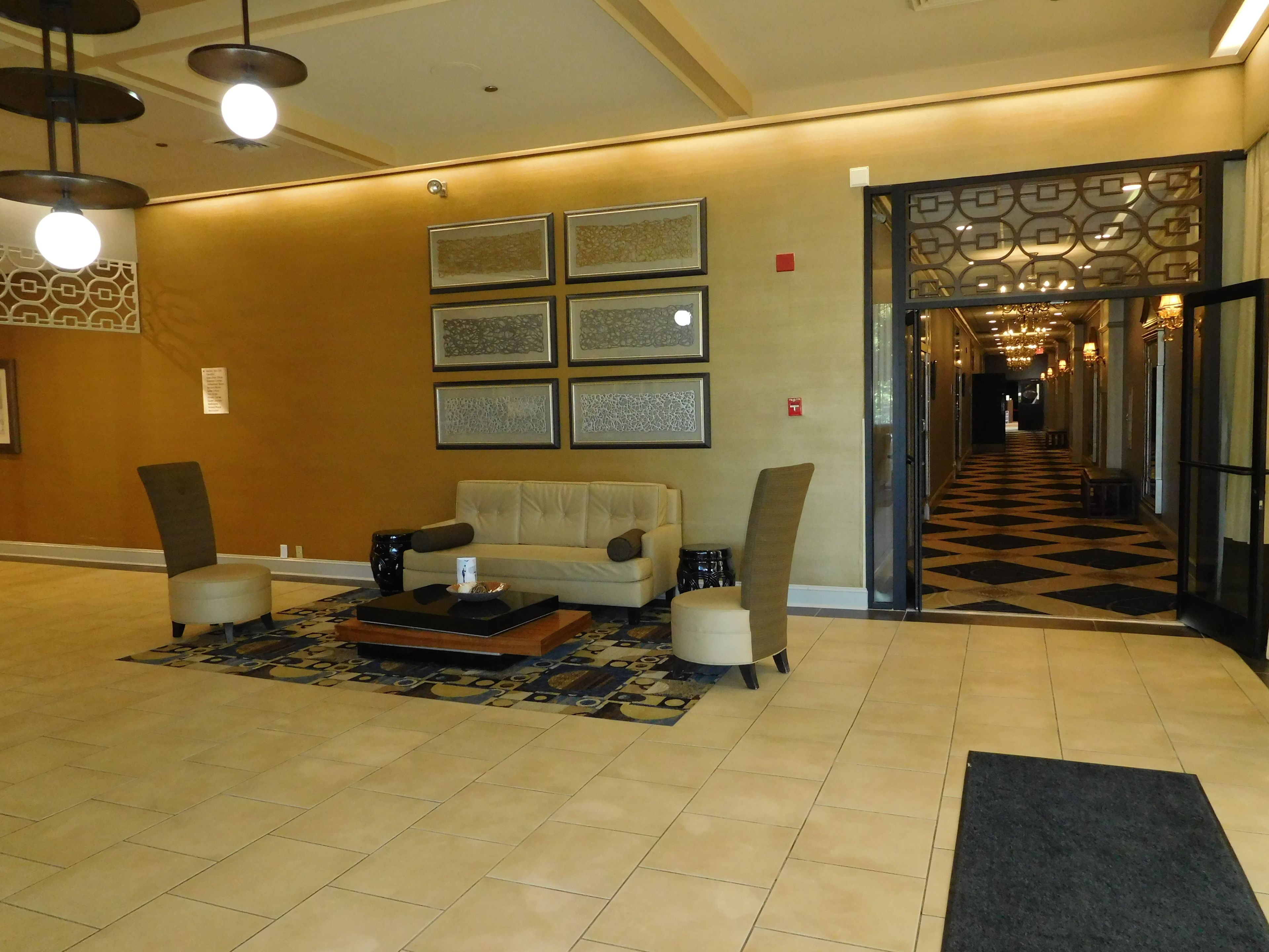 A lobby with a sofa, chairs, a coffee table, and framed artwork on the wall.
