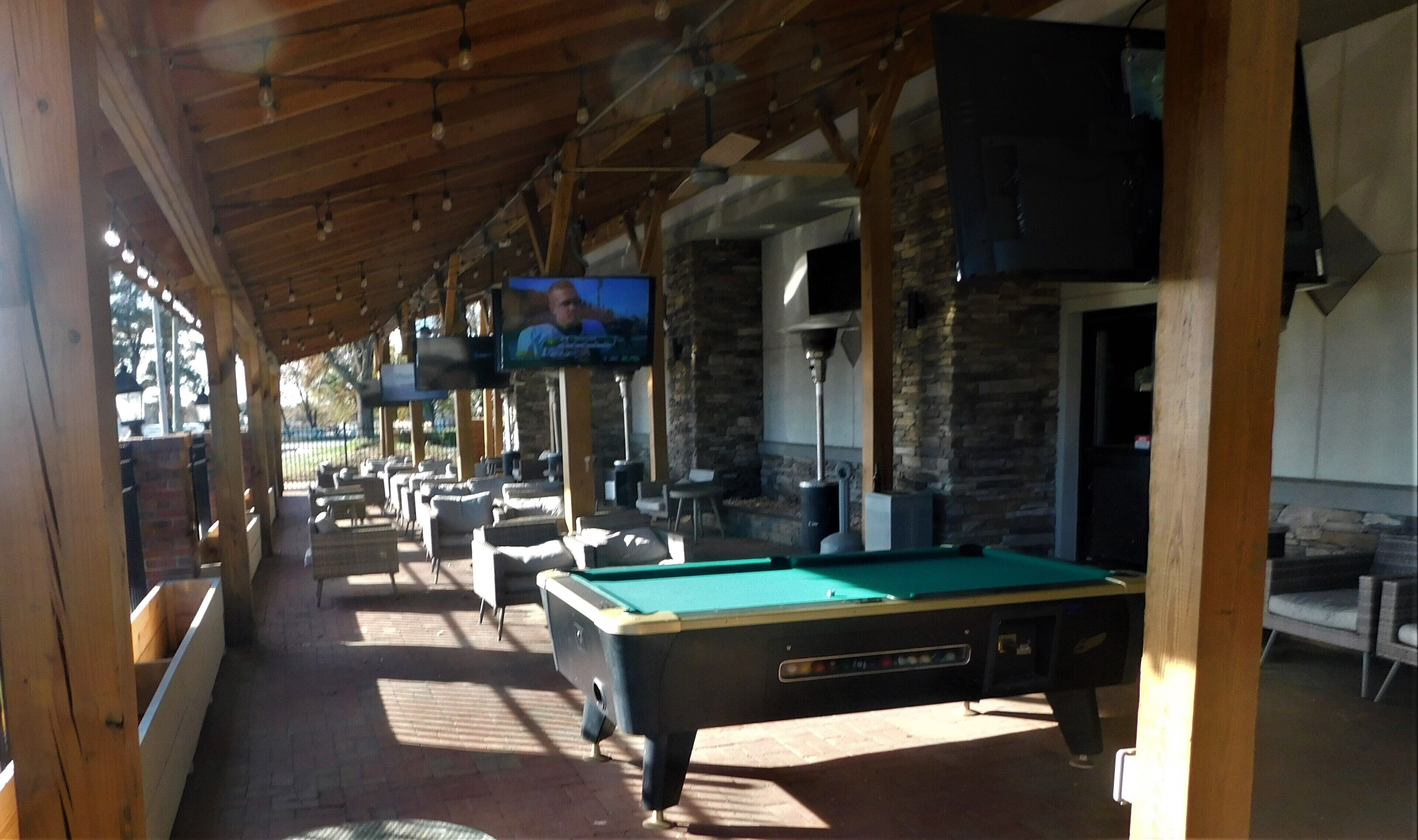 A covered outdoor area with pool tables and seating.