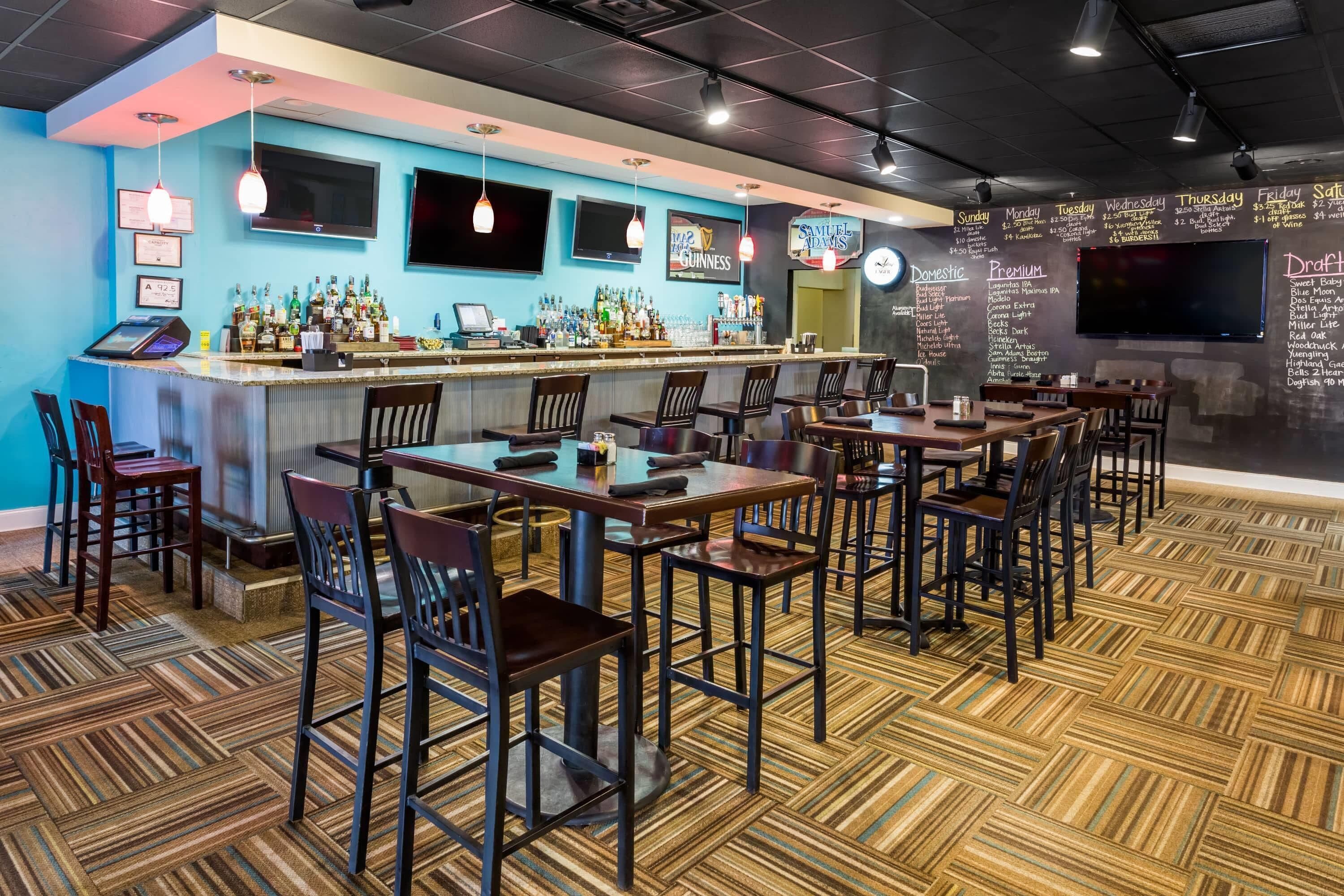Een bar met een toonbank, barstoelen en een menukaart.