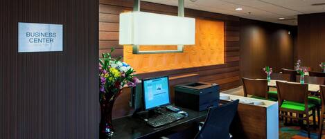A business center with a reception desk, computer, and chairs.