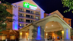 Ein Holiday Inn Express & Suites Gebäude mit einer auffälligen Beschilderung, einem überdachten Eingang und einem Brunnen.