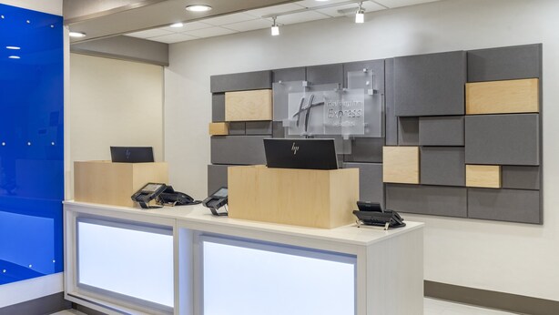 Ein Hotelrezeptionstresen mit zwei HP-Laptops, einem Telefon und einem Schild für Holiday Inn Express & Suites.