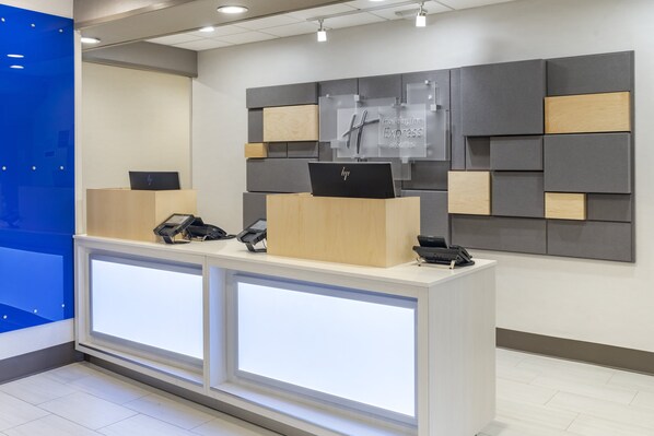 A hotel reception desk with two HP laptops, a phone, and a sign for Holiday Inn Express & Suites. - Holiday Inn Express Hotel & Suites Albuquerque Midtown by IHG (Albuquerque)