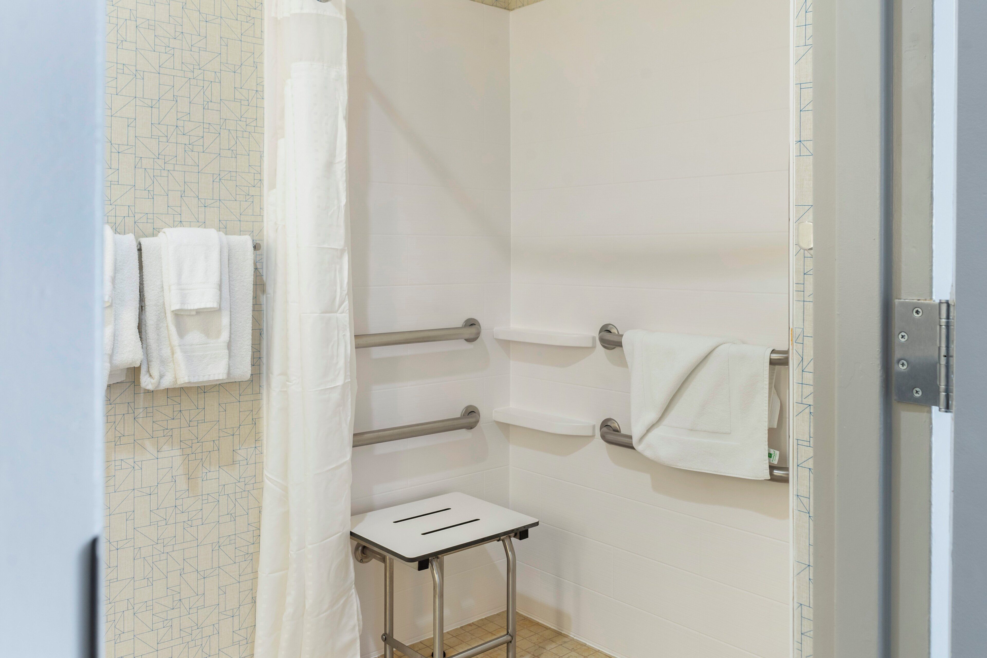 Een badkamer met een douche, een handdoekhouder en een klein tafeltje.