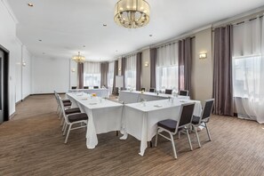 A conference room with a long table, chairs, a chandelier, and large windows with curtains. - Days Inn & Conference Centre by Wyndham Montreal Airport (Montreal)